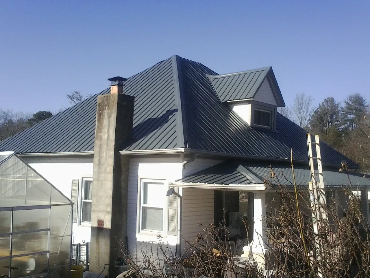 Dark blue standing seam metal roof on a white farmhouse with dormer — Slate & Tile Roof Repair by Roofing Brothers in Cobbs Creek