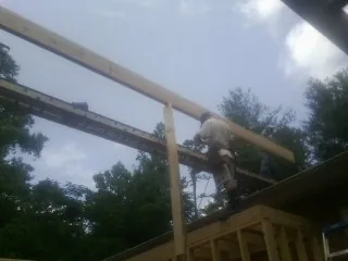 Carpenter setting a ridge beam over a new addition frame — Ice Dam Removal by Roofing Brothers in Cobbs Creek