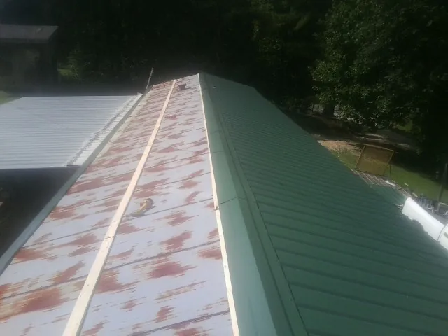 Old rusted panels beside newly installed green metal roofing — Wind Damage Roof Repair by Roofing Brothers in Cobbs Creek