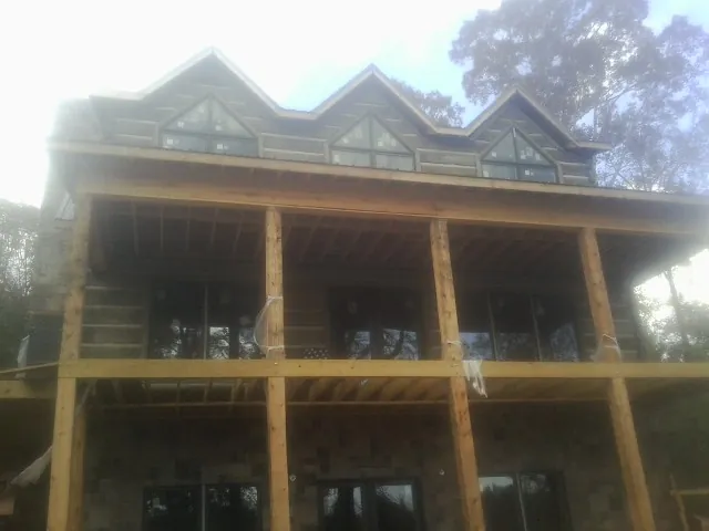 Dormers and porch framing on a large log home under construction — Roof Coating work by our crew in Cobbs Creek
