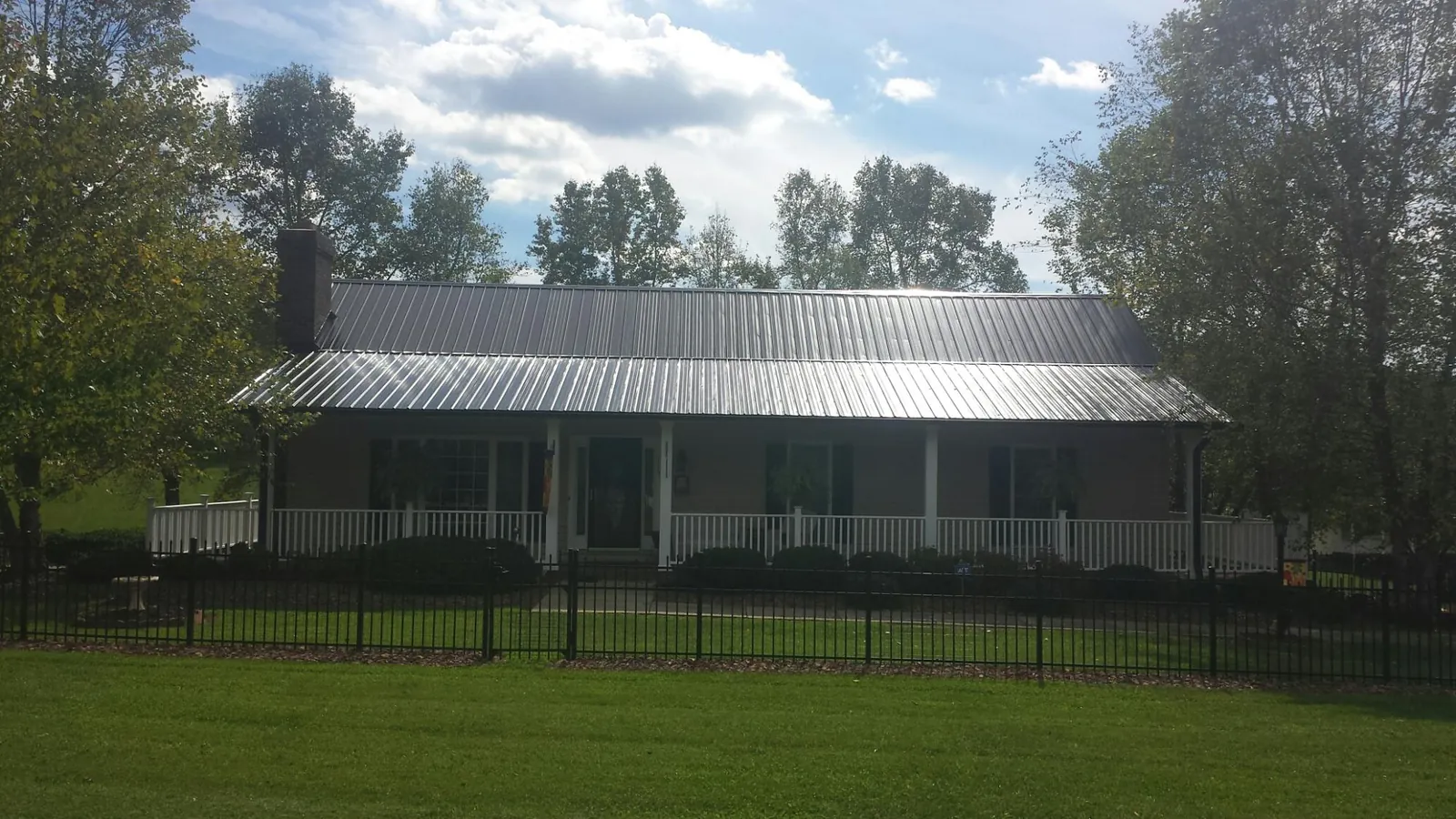 Gray metal roof on a brick ranch with a full width front porch — Gutter Guard Installation work by our crew in Cobbs Creek