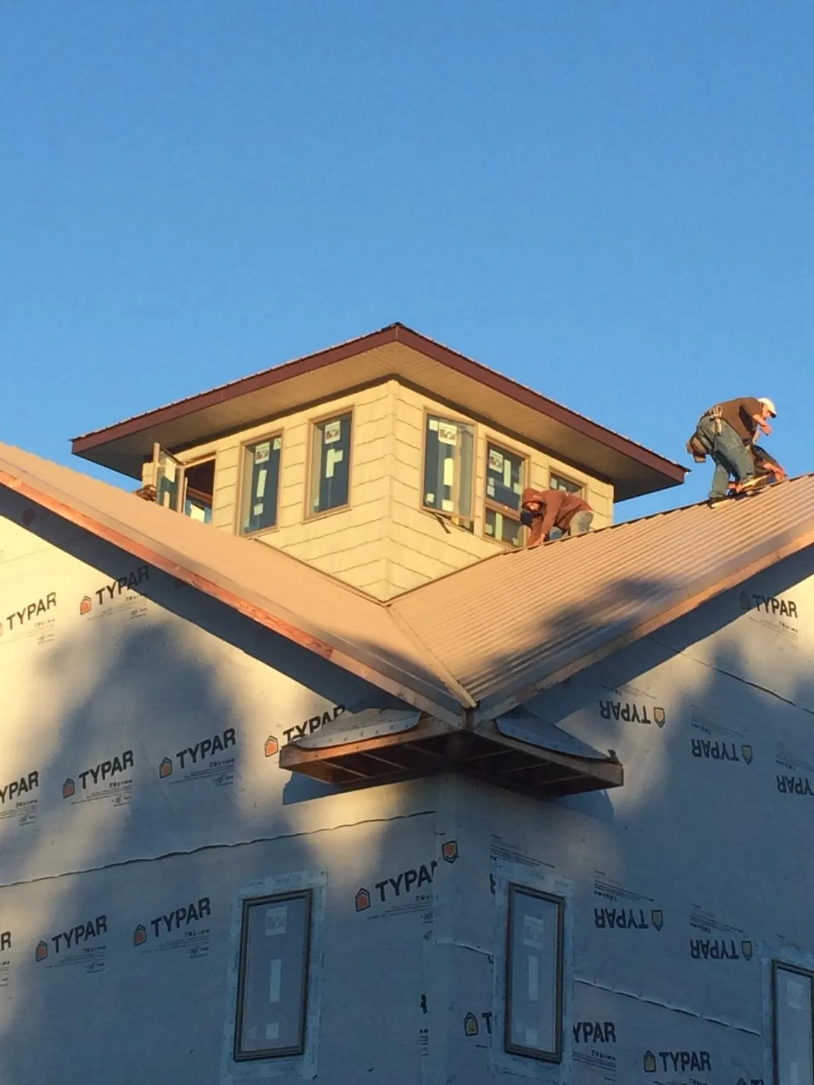 Roofers working around a rooftop cupola on a new metal roof at sunset — Roof Waterproofing in Cobbs Creek by Roofing Brothers